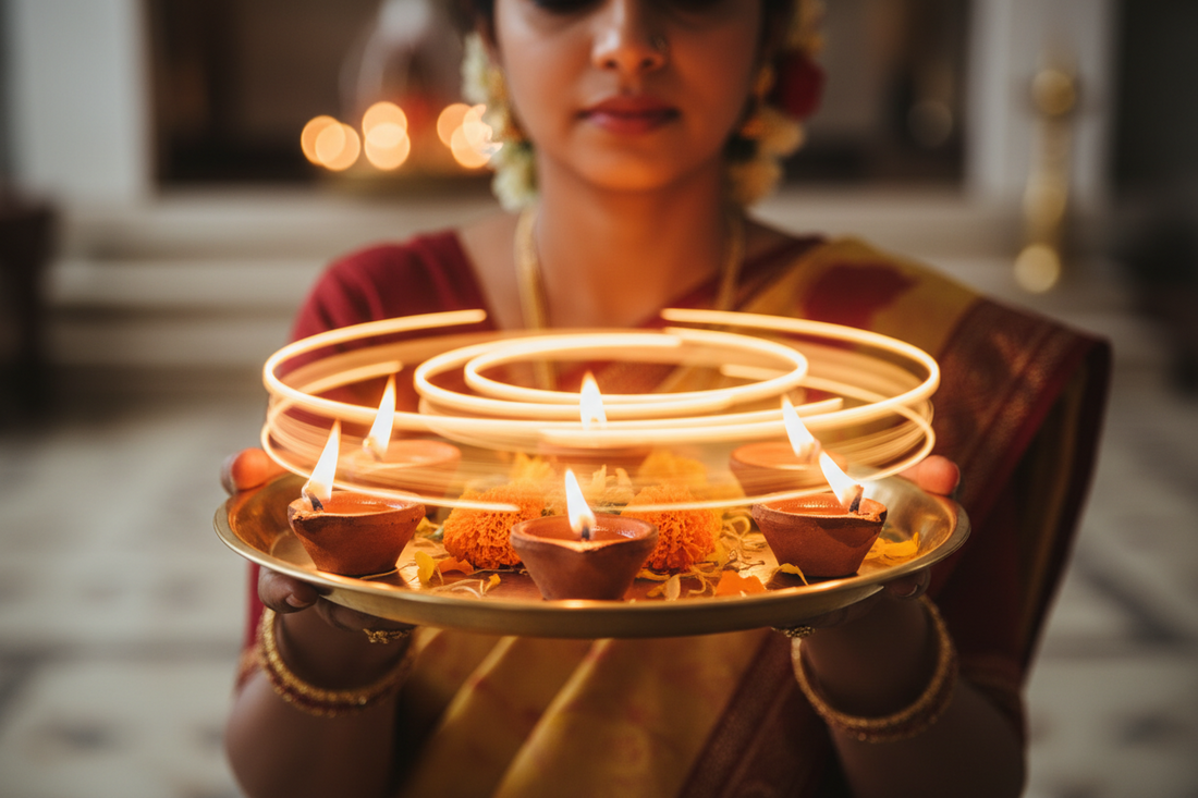Woman's hands performing aarti with brass thali five lit diyas and marigolds
