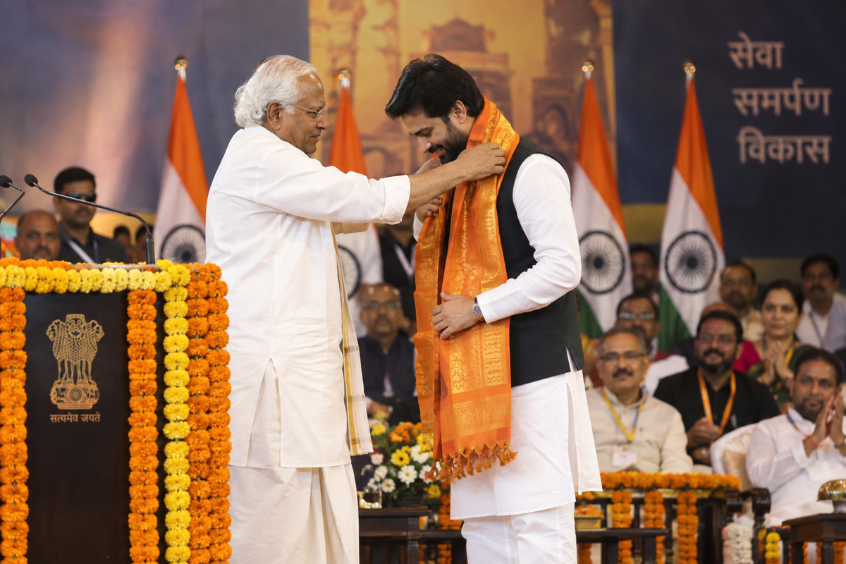Senior Indian statesman draping saffron stole on honoured leader at formal felicitation stage ceremony